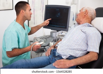 Man Doctor Pointing To Monitor During Examination A Mature Man With Ultrasound