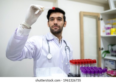 Man Doctor Or Specialist In Lab Coat Wearing Glove And Looking At Test Tube Sample In The Clinic. There Are Many Tube Sample In The Rack On The Tray. Laboratory, Testing And Lifestyle Concept.