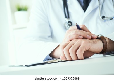 Mann Arzt mit Stethoskop, der die Armbanduhr anschaut. Doktor in weißer Uniform auf Bürohintergrund, der auf Patienten wartet. Zeit zum Besuch des Therapeuten.