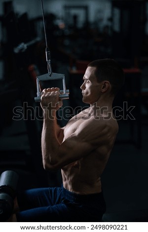 A man does a chest pulldown in the gym.