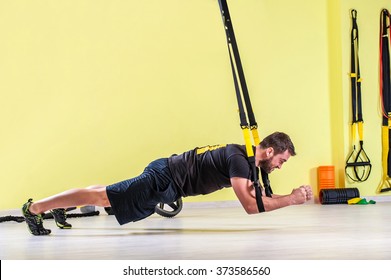 Man does crossfit push ups with trx fitness straps in the gym's studio