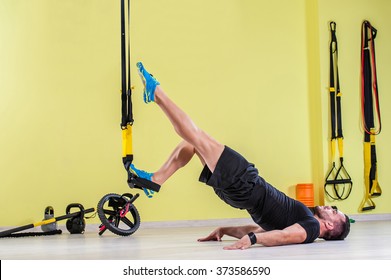 Man does crossfit push ups with trx fitness straps in the gym's studio