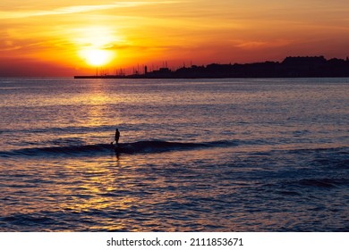 Man does stand up paddle overlooking the coast of Estoril near Lisbon, Portugal at sunset - with copy space