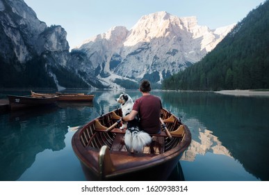 Man And Dog In A Boat On A Mountain Lake. Traveling With A Pet To Italy. Australian Shepherd Dog And Its Owner