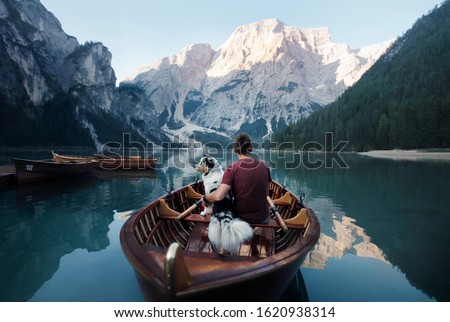 man and dog in a boat on a mountain lake. Traveling with a pet to Italy. Australian Shepherd Dog and its owner