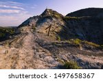 A man and dog hike across Devil’s Pass in late afternoon light. Maah Daah Hey Trail, North Dakota.