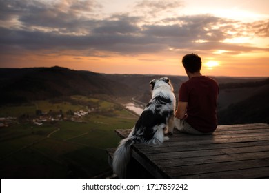 A Man With A Dog At Sunset. Walk With A Pet. Australian Shepherd And Owner In Nature