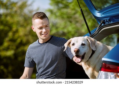 Man With Dog Traveling By Car. Pet Owner Enjoying Road Trip With His Labrador Retriever.
