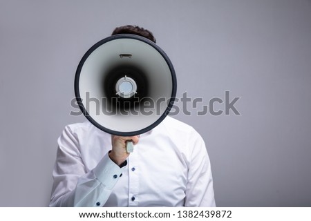 Man Doing Announcement Using Megaphone Against Gray Background