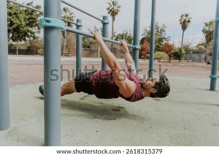 A man is doing Australian pull ups doing his workout outside, horizontal photo.