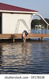 A man is doing a back flip off the end of a dock into the water
