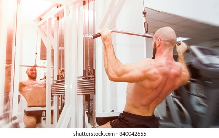 Man Doing Back Pullups In The Mirror At The Gym With A Energy Powerful Look And Feel With Soft Filters Applied Suggesting A Hard Workout