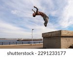 Man doing back somersault. Parkour athlete training in city in sportive clothes. Free runner jumping have workout. Active lifestyle. Extreme sports, outdoor freerun