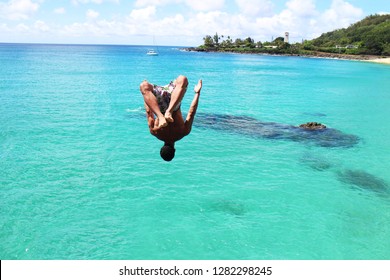 Man Doing Backflip Off Cliff Into The Ocean. Diving Cliff Ocean. Summer Fun Lifestyle