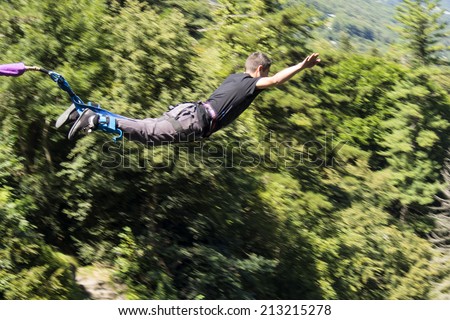a man doing bungee jumping with a forest in background, extreme sports 