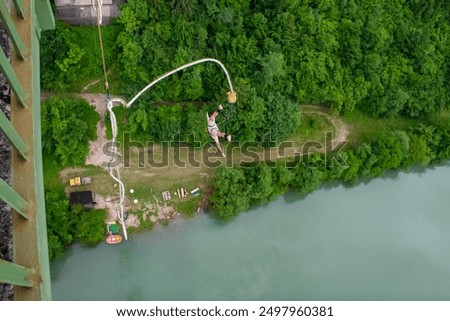 Man doing bungee jumping on Jauntal bridge in Southern Carinthia, Austria, Europe. Surge of adrenaline. Ultimate rush of freefall. Vertiginous drop unfolds dense lush green forest. Overcoming fear