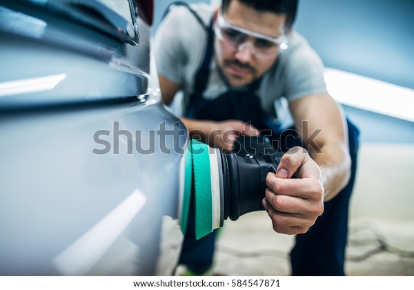Man doing a car polish\
with a machine.