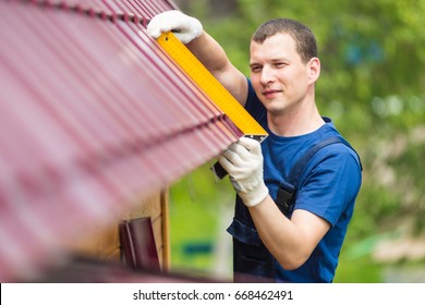The man is doing a check on the new red roof - Shutterstock ID 668462491