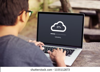 Man doing cloud uploading on laptop / computer at the park / outdoor