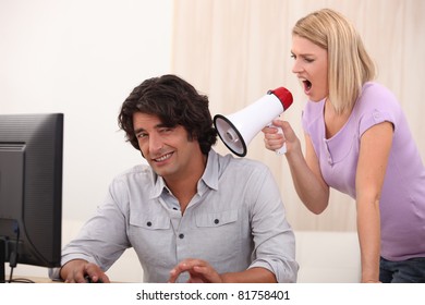 a man doing computer and a woman yelling on him with a megaphone - Shutterstock ID 81758401