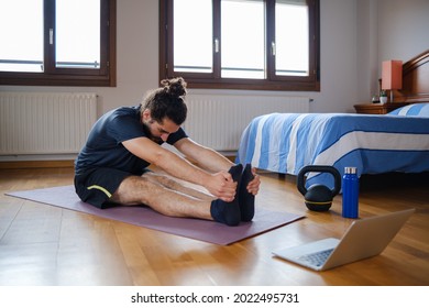 Man Doing Deep Stretches At Home During An Online Exercise Class.