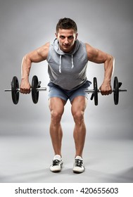 Man Doing Dumbbell Row Over Gray Background In Studio