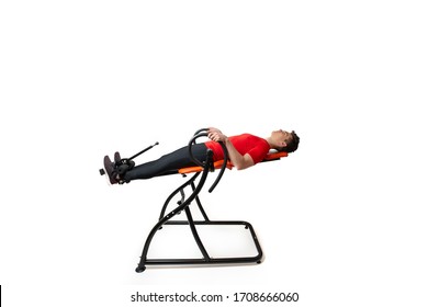 Man doing exercise on inversion table for his back pain, isolated on white