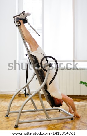 Man doing exercise on inversion table for his back pain