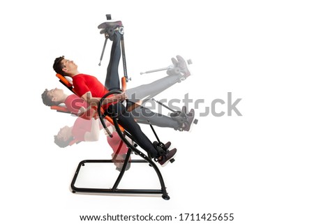 Man doing exercise on inversion table for his back pain, isolate