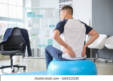 Man Doing Exercises With Fitness Ball In Office