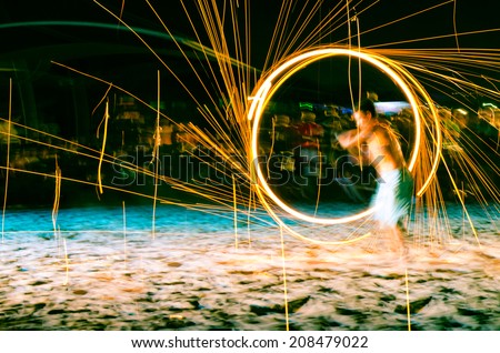 man doing fire show on beach at night