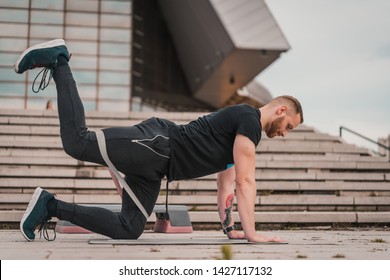 Man Doing Fitness Exercises With Elastic Resistance Band. Handsome Young Man Training With Rubber Band. Sportsman Doing Workout Outdoors. Healthy Lifestyle Concept