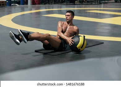 Man Doing Fitness Workout, Practicing Abs Exercise With Med Ball At Street. Male Athlete Exercising, Doing Russian Twist With Medicine Ball Outdoors