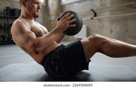 Man doing fitness workout, practicing abs exercise with med ball in gym