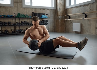 Man doing fitness workout, practicing abs exercise with med ball in gym