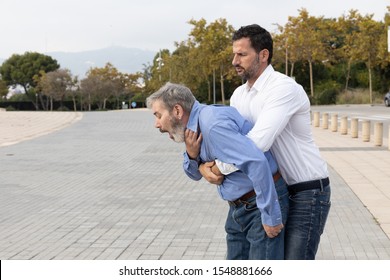 Man doing the Heimlich maneuver to an old man with suffocation due to obstruction of the airway with food