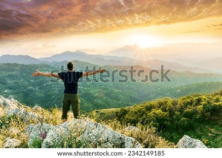 man doing hiking sport in mountains with anazing highland view, happy person watching amazing highland evening sunset, person delight with nature landscape