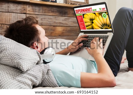 Man doing his grocery shopping by internet with a laptop while rest on the couch at home