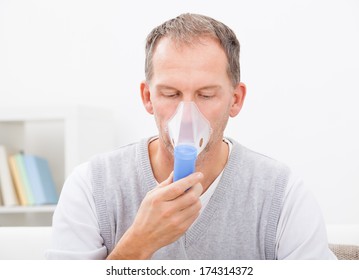 Man Doing Inhalation Through Oxygen Mask At Home