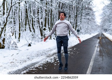 Man doing jumping jacks as a warmup before jogging on a winter day - Shutterstock ID 2254862059