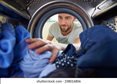 Man Doing Laundry Reaching Inside Washing Machine