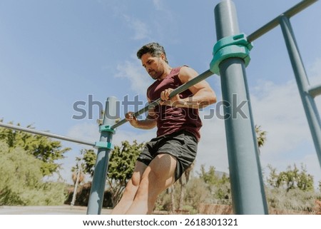 A man is doing a muscle up while training at an outdoor gym, strength concept.