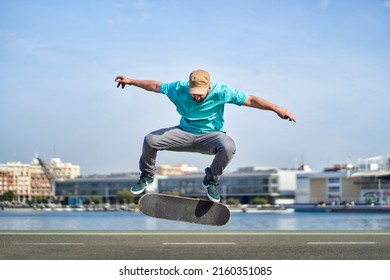 a man doing an ollie flip with his skateboard down a road