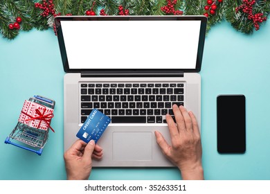 Man Doing Online Shopping With Credit Card On Laptop. Overhead Of Essentials For Modern Young Person.Different Objects On Cyan Blue Background. Close -up Hand On Laptop