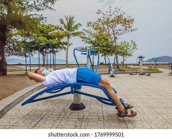 Man doing physical exercises, push ups, strength exercises, leans in empty outdoor public city park metal gym wearing mask alone for Covid19 prevention. Healthy lifestyle in quarantine and coronavirus - Powered by Shutterstock