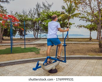 Man doing physical exercises, push ups, strength exercises, leans in empty outdoor public city park metal gym wearing mask alone for Covid19 prevention. Healthy lifestyle in quarantine and coronavirus - Powered by Shutterstock