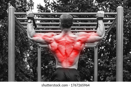 Man doing pull-ups on a  horizontal bar during his calisthenics workout on a street