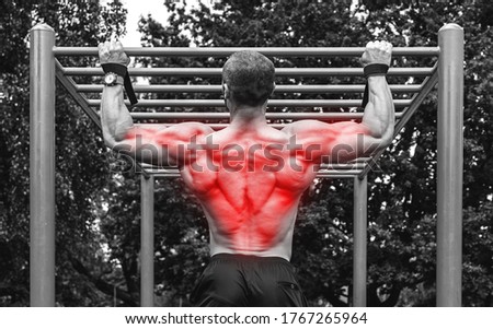 Man doing pull-ups on a  horizontal bar during his calisthenics workout on a street