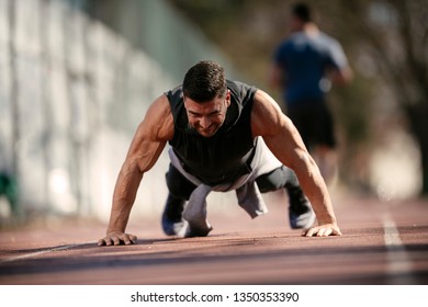 Man doing a push up. Trainer exercises outdoors.