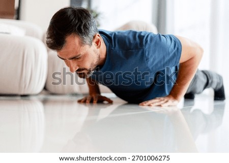 Man doing push ups on the living room floor, focused on his home fitness routine